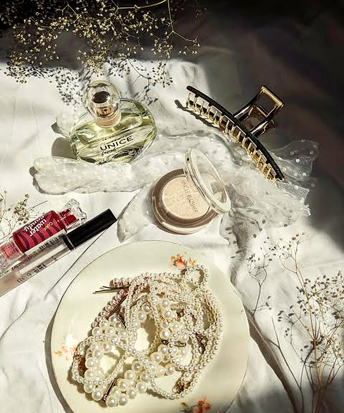 Perfume, compact and cosmetics arranged on ivory linen